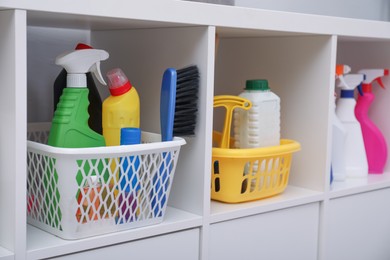 Photo of White shelving unit with set of detergents and cleaning tools