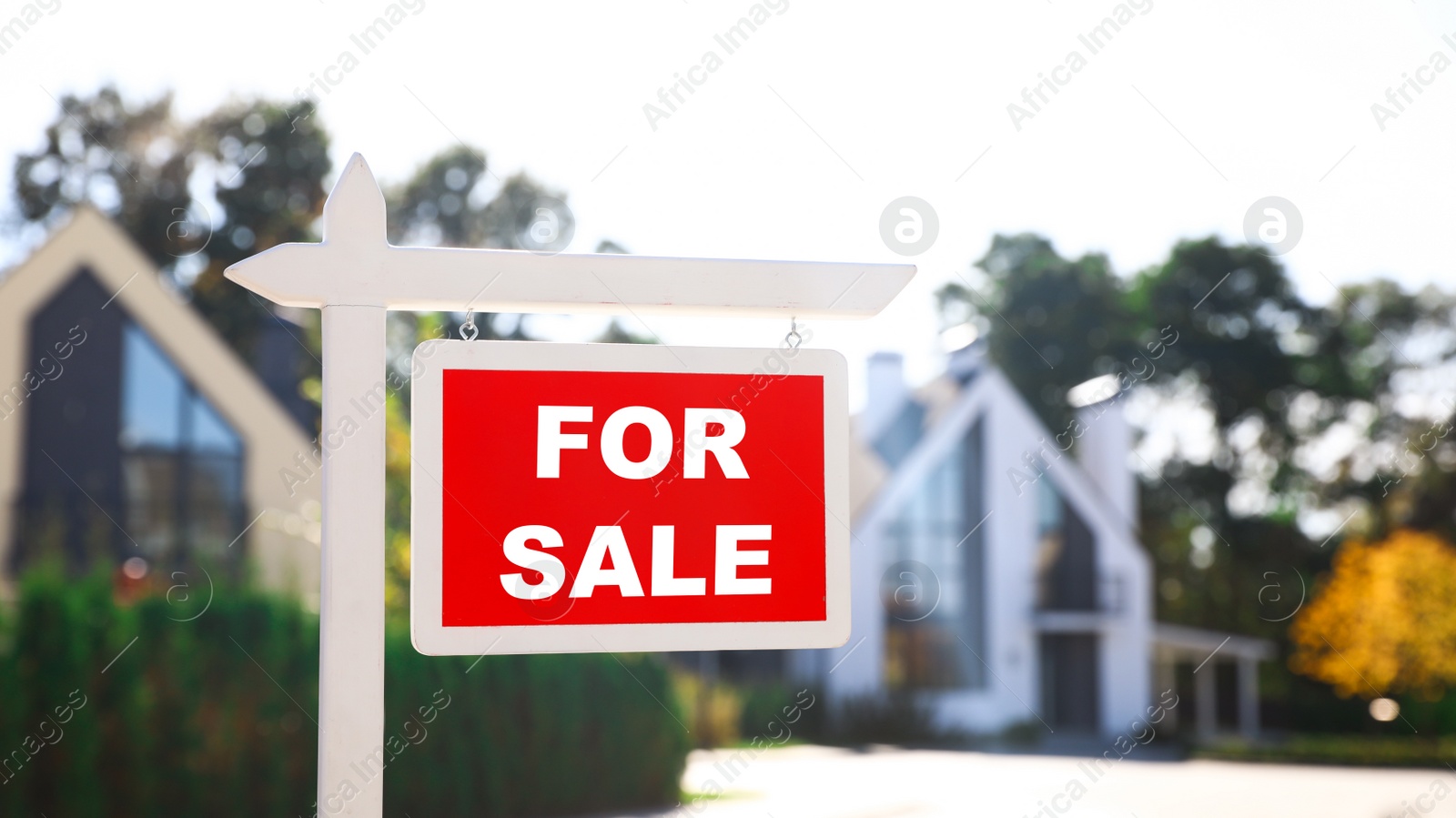 Photo of Red real estate sign near house outdoors on sunny day