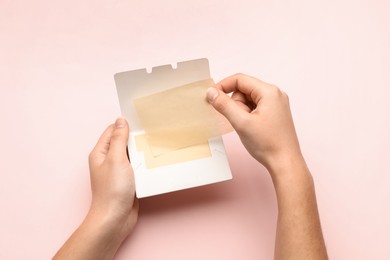 Photo of Woman with package of oil blotting tissues on pink background, top view. Mattifying wipes