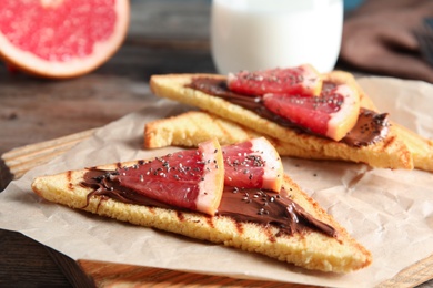 Photo of Tasty toasts with grapefruit, chocolate paste and chia seeds on board