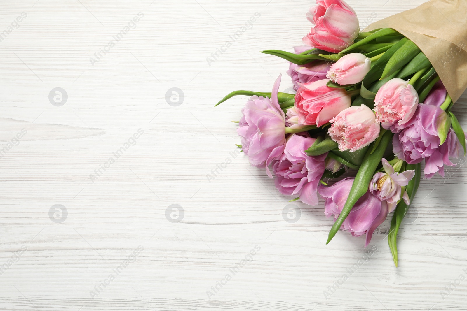 Photo of Beautiful bouquet of colorful tulip flowers on white wooden table, top view. Space for text