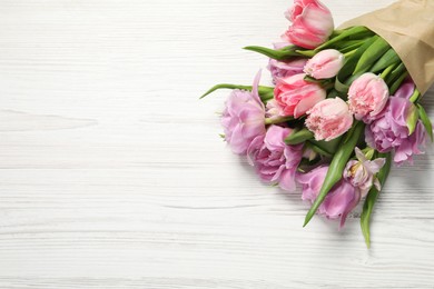 Photo of Beautiful bouquet of colorful tulip flowers on white wooden table, top view. Space for text