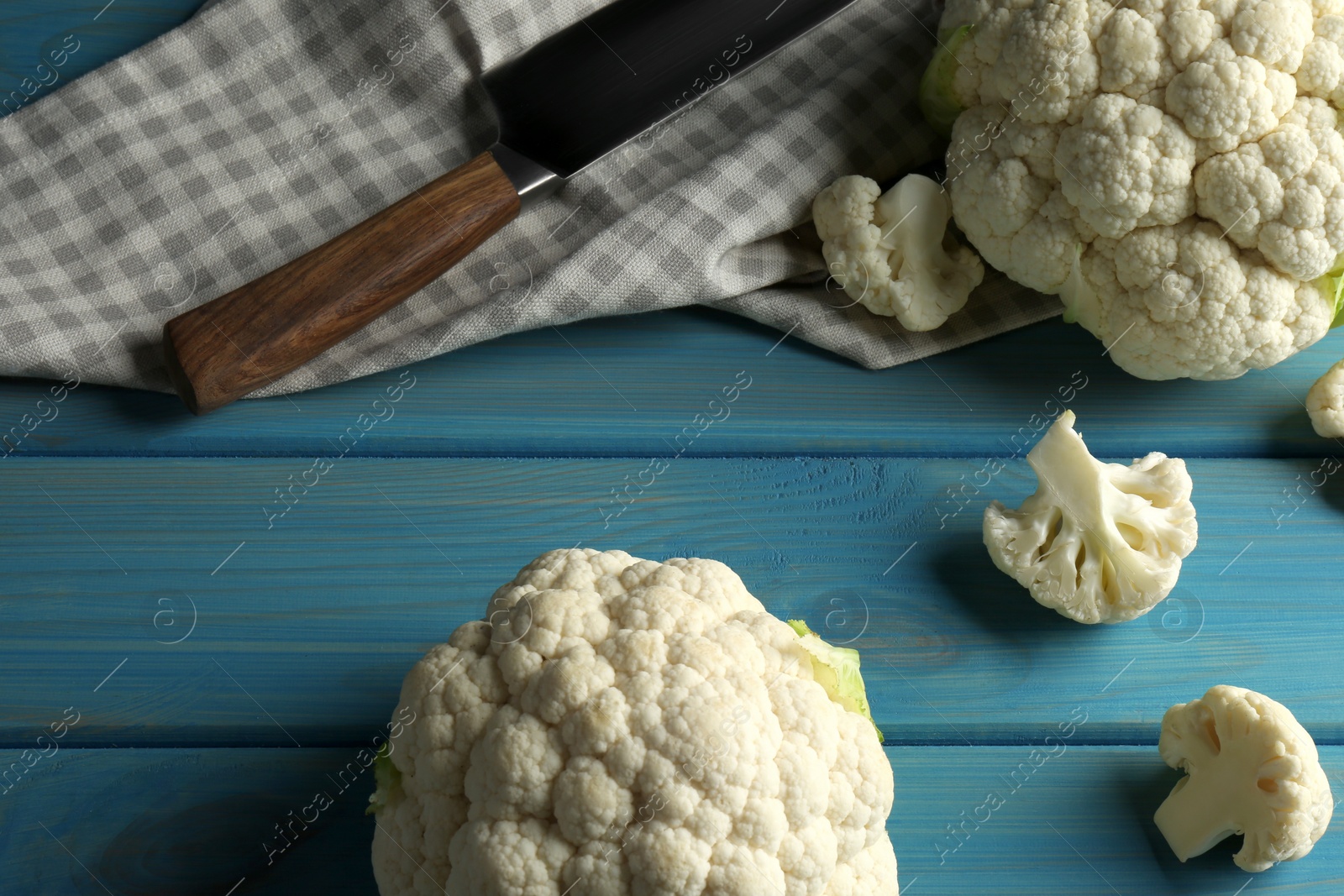 Photo of Fresh whole and cut cauliflowers on light blue wooden table