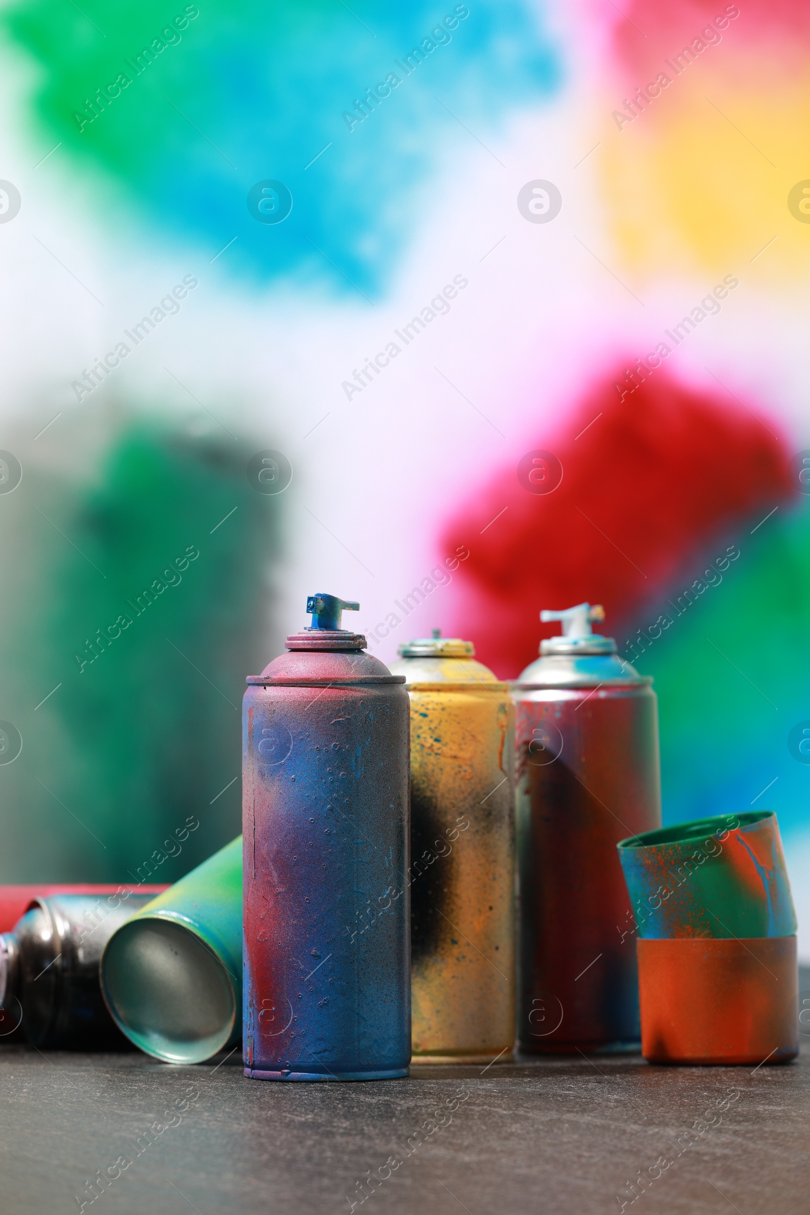 Photo of Many spray paint cans on gray surface against color background