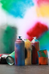 Photo of Many spray paint cans on gray surface against color background