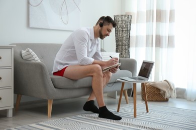 Businessman in underwear pretending to wear formal clothes during video call at home