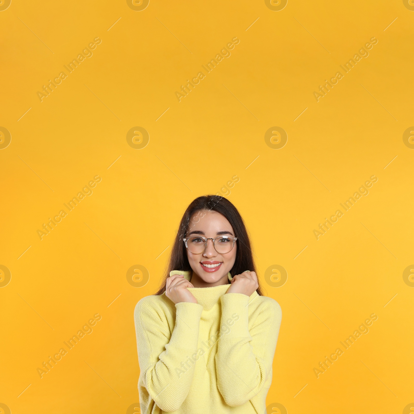 Photo of Beautiful young woman wearing warm sweater on yellow background. Space for text