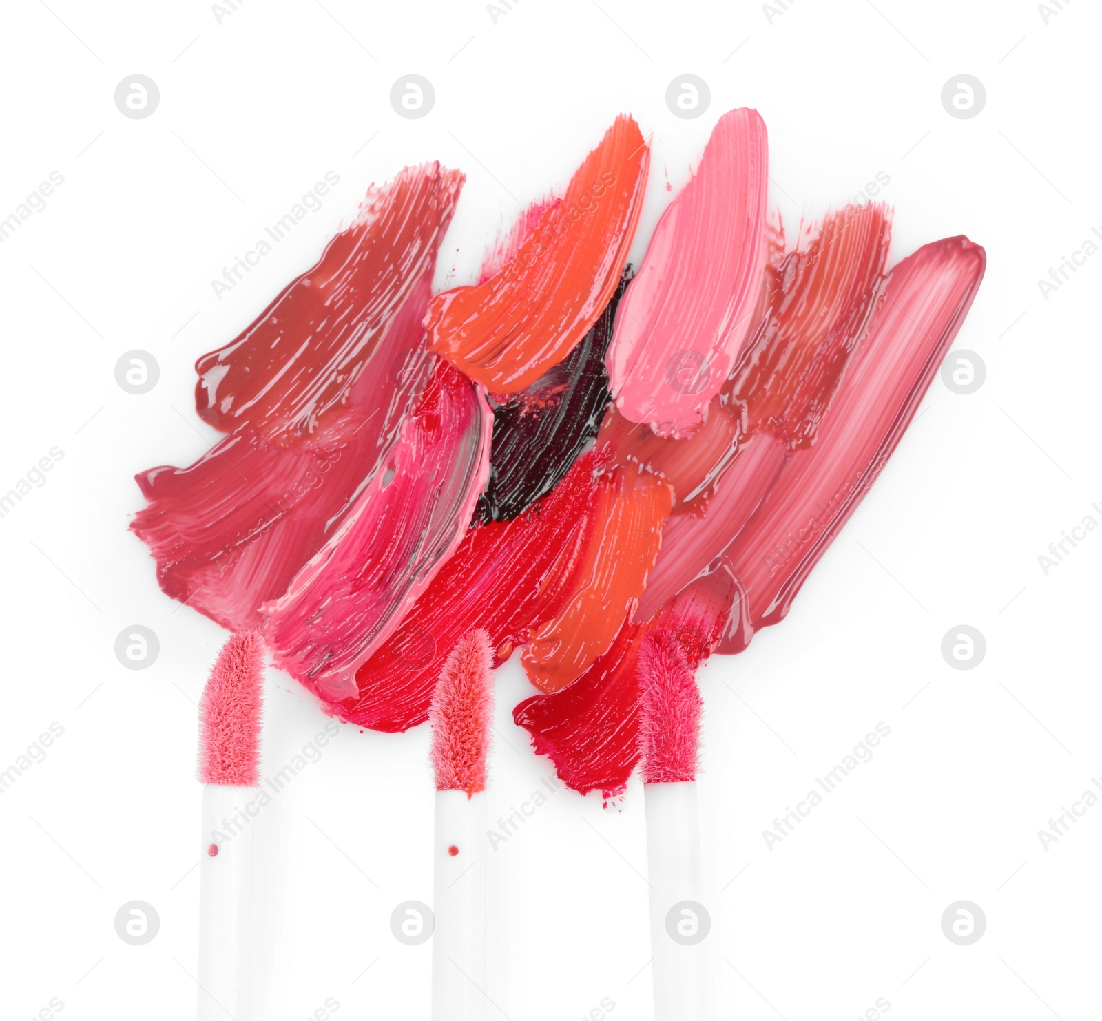 Photo of Strokes of different lip glosses and applicators isolated on white, top view