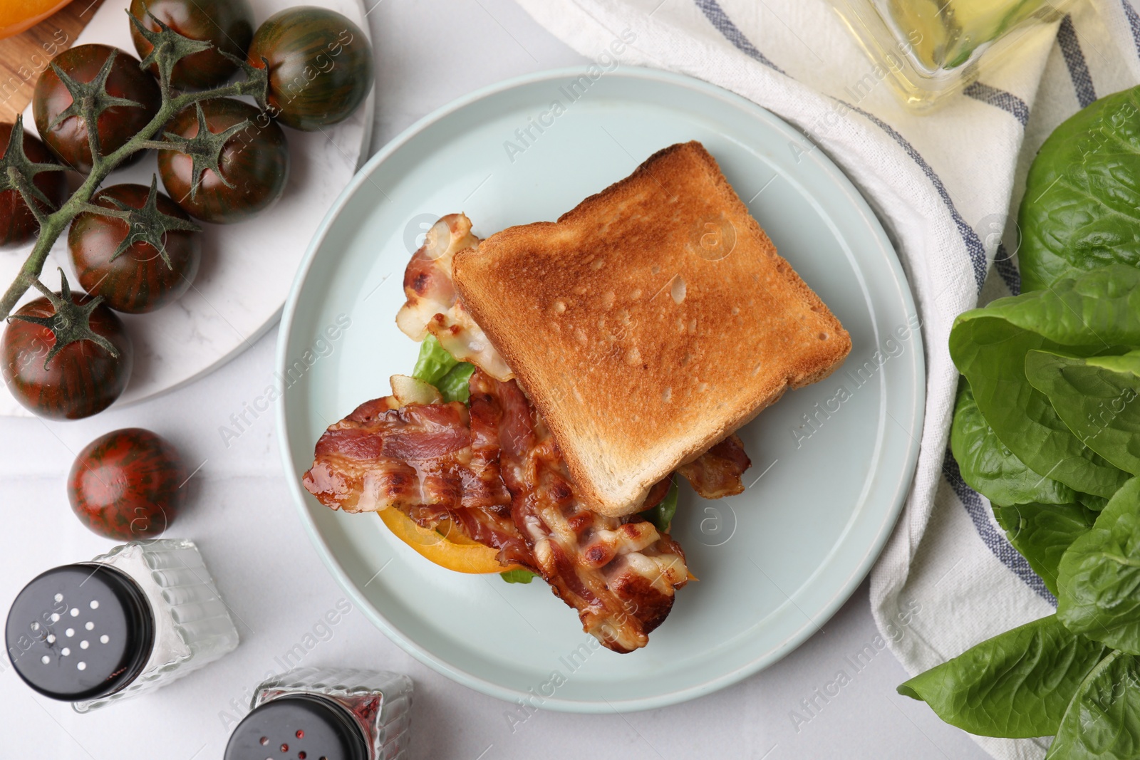 Photo of Tasty sandwich with bacon, tomatoes and spices on white table, flat lay