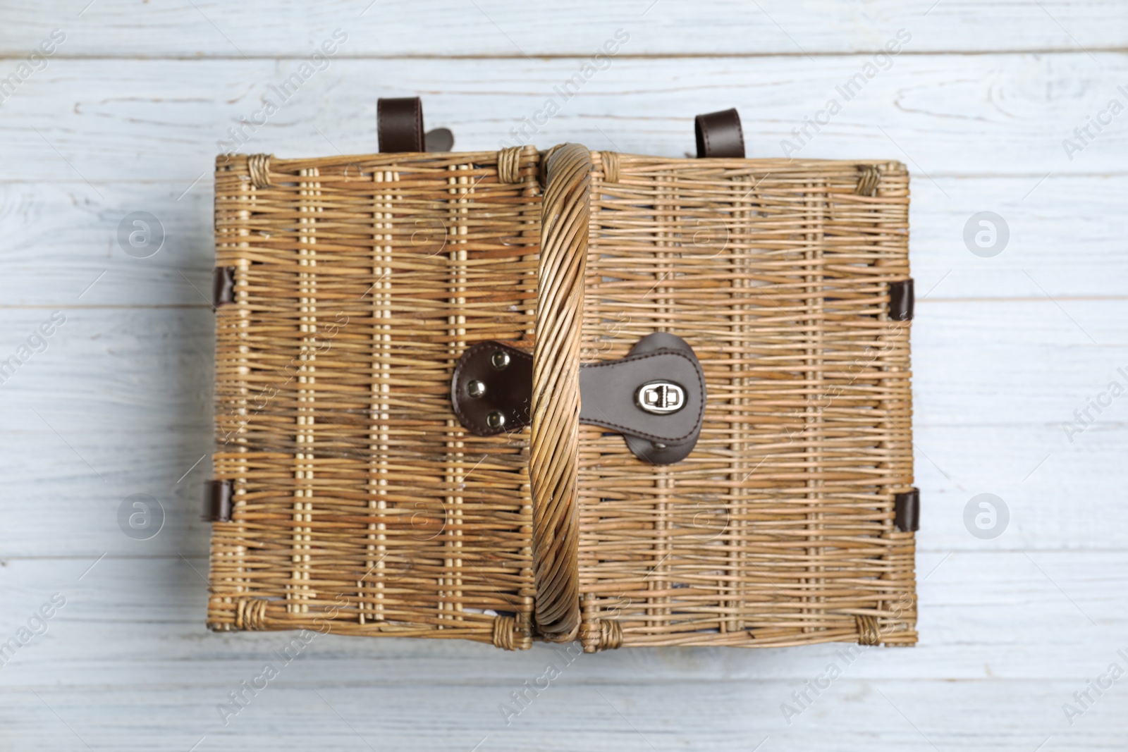 Photo of Closed wicker picnic basket on wooden table, top view