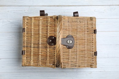 Photo of Closed wicker picnic basket on wooden table, top view