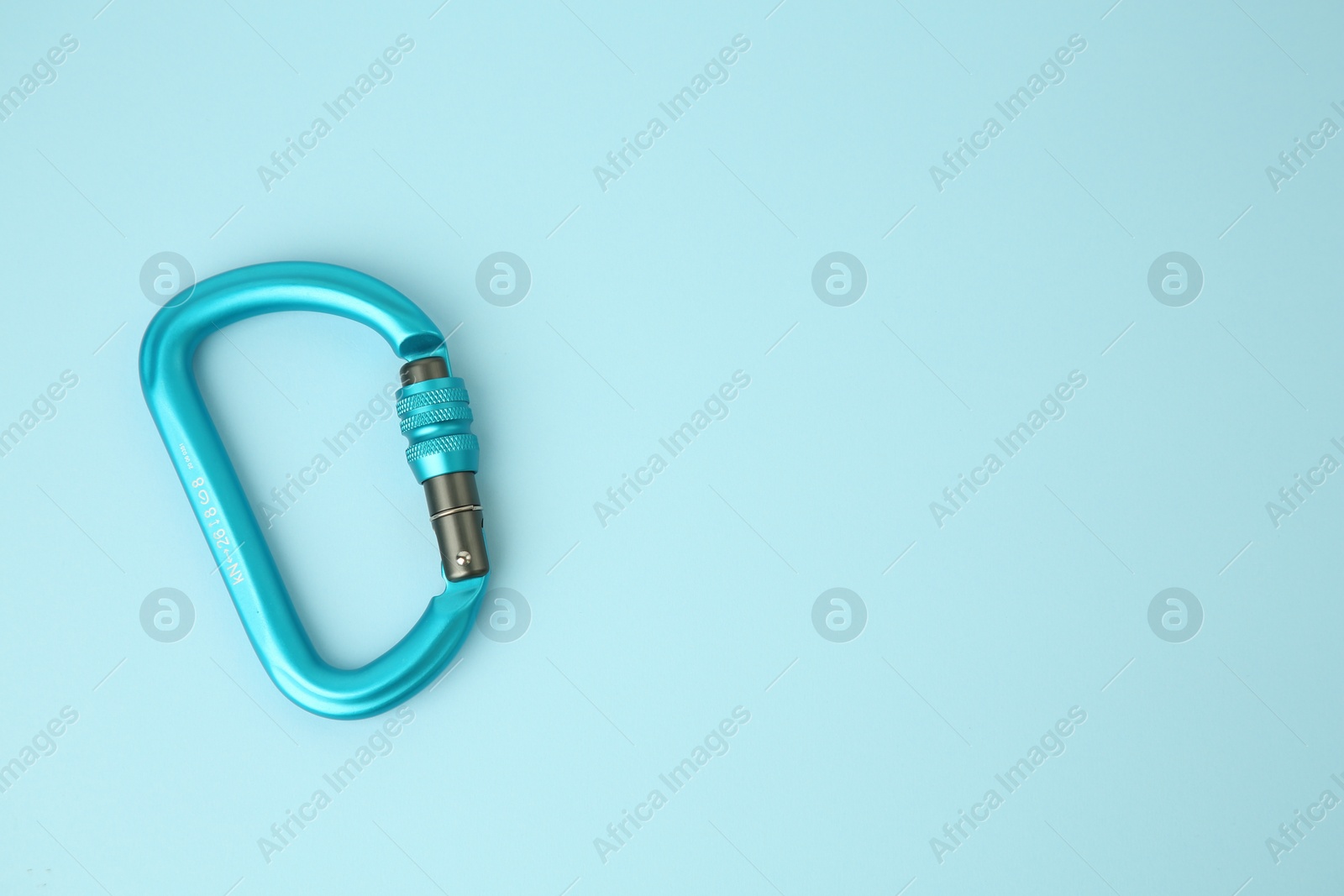 Photo of One carabiner on light blue background, top view. Space for text
