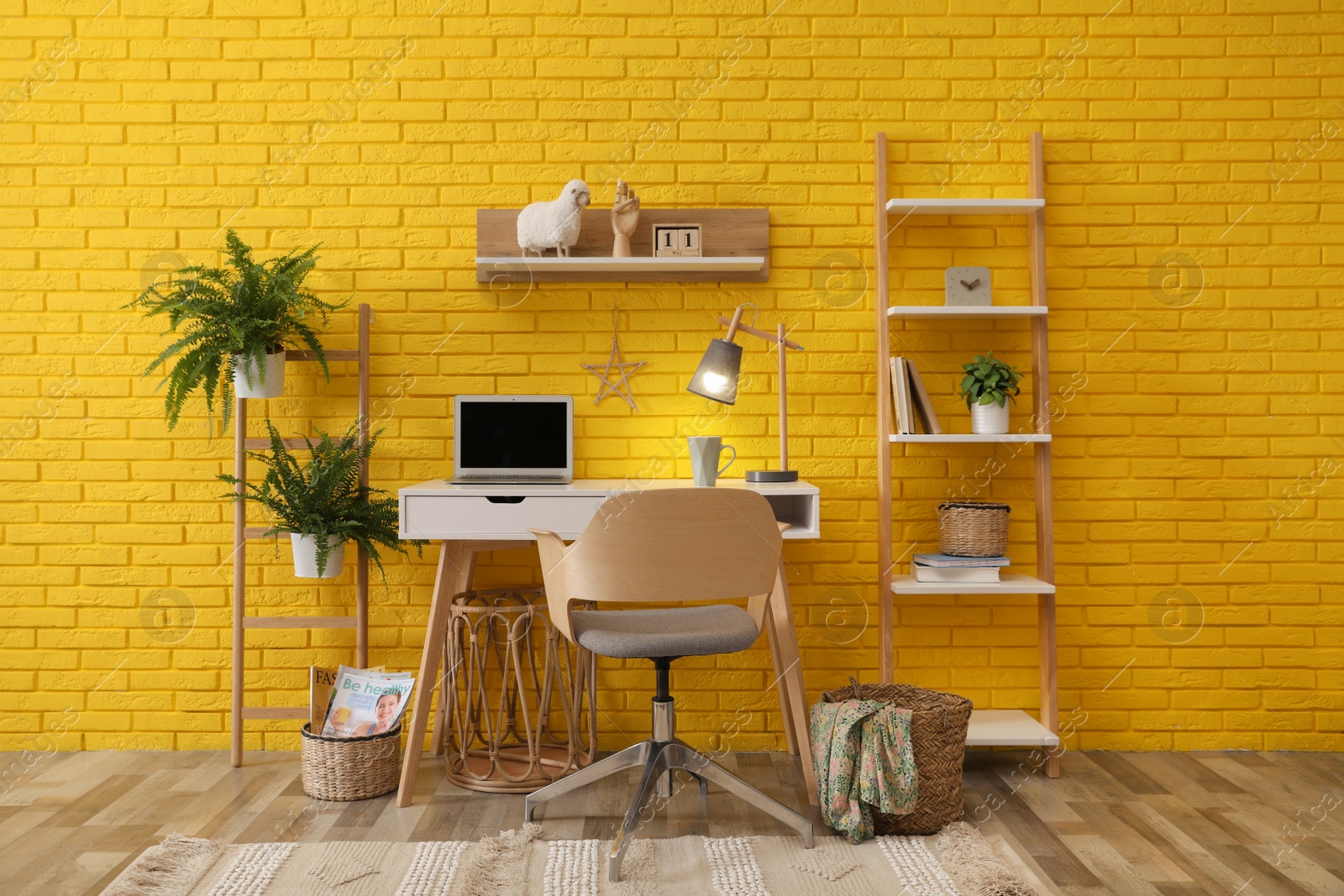 Photo of Modern workplace interior with wooden furniture and laptop near yellow brick wall