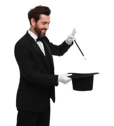 Happy magician showing magic trick with top hat on white background