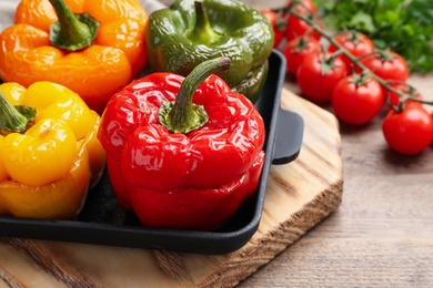 Photo of Tasty stuffed bell peppers in baking pan on wooden table, closeup