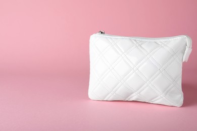 White leather cosmetic bag on pink background. Space for text