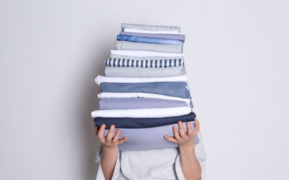 Photo of Woman holding stack of clean bed linens on white background