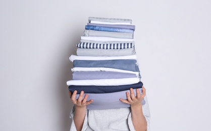 Woman holding stack of clean bed linens on white background