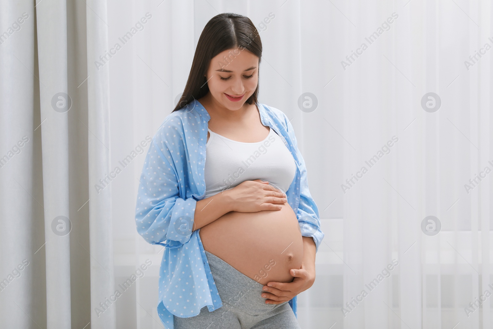 Photo of Beautiful pregnant woman in blue shirt indoors