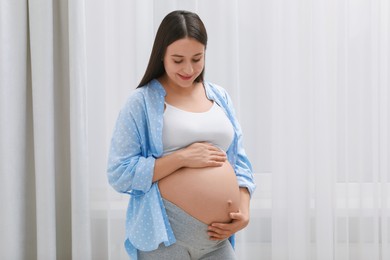 Photo of Beautiful pregnant woman in blue shirt indoors