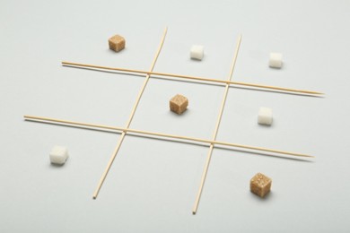 Photo of Tic tac toe game made with sugar cubes on light background