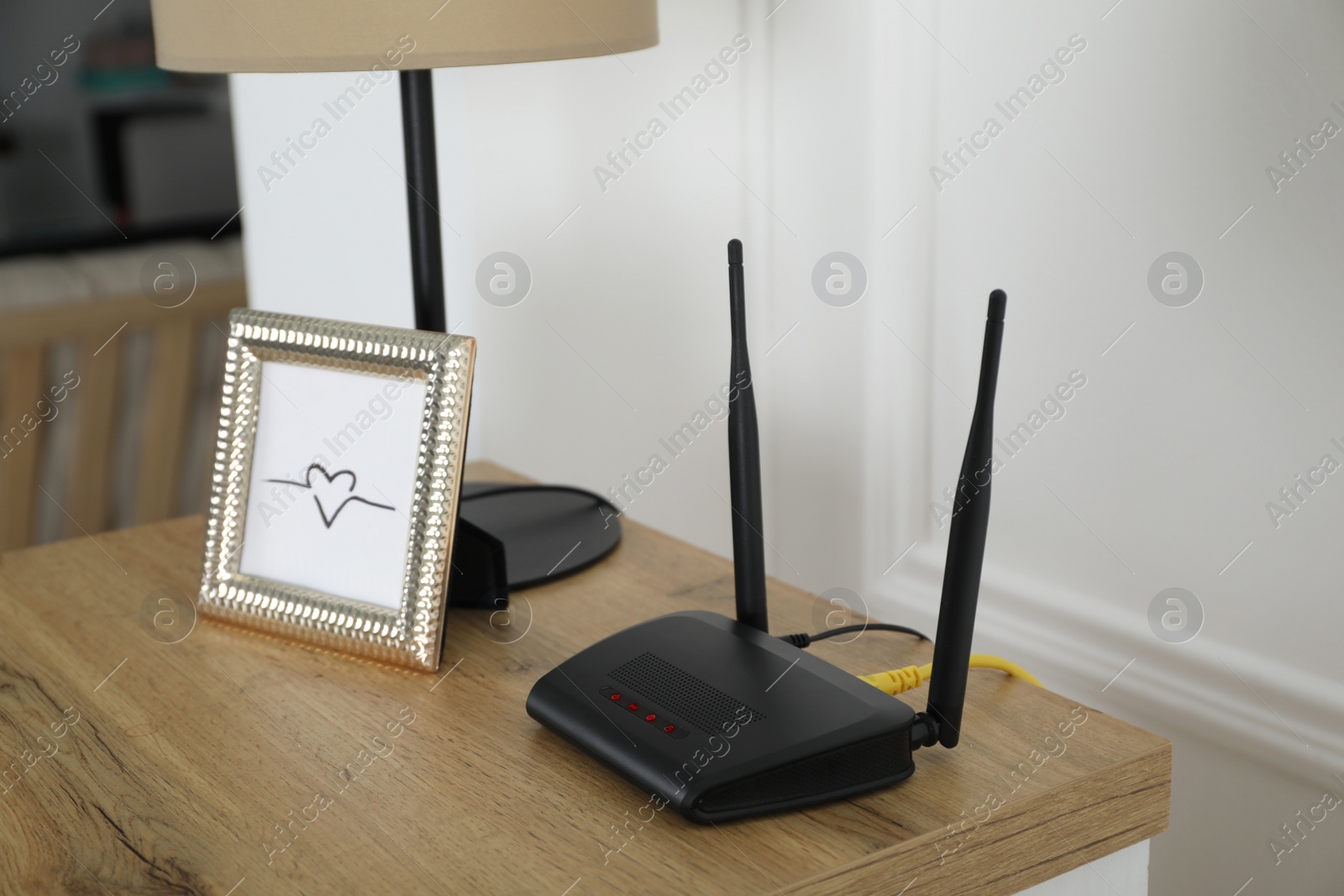 Photo of Modern Wi-Fi router on wooden table in room