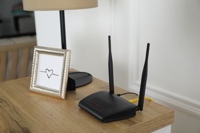 Photo of Modern Wi-Fi router on wooden table in room