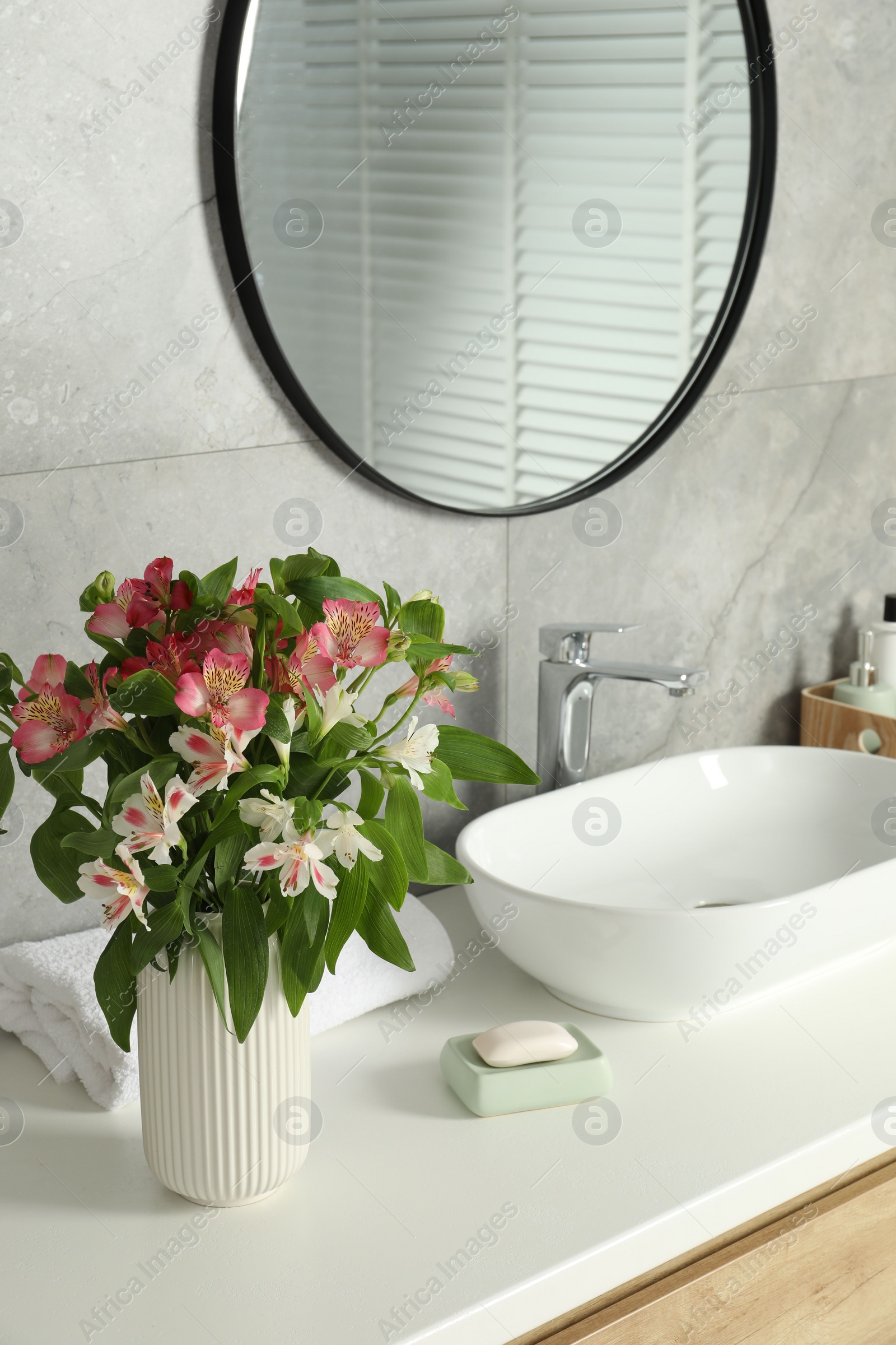 Photo of Vase with beautiful Alstroemeria flowers near sink in bathroom