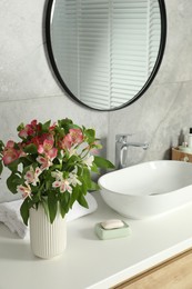 Vase with beautiful Alstroemeria flowers near sink in bathroom