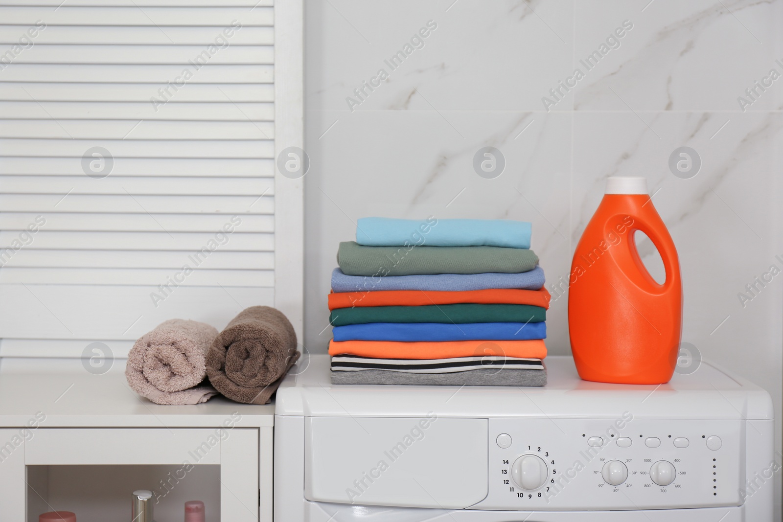 Photo of Fresh laundry and detergent on washing machine in laundry room