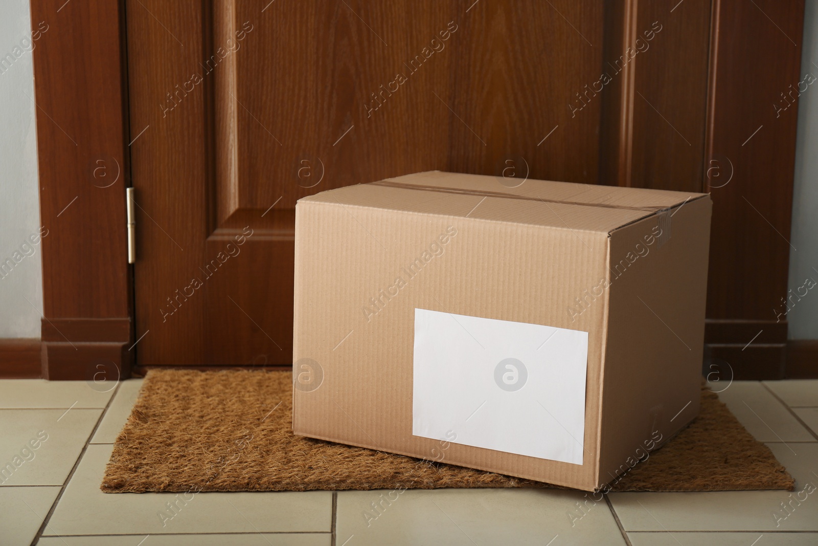 Photo of Parcel on rug near door. Delivery service