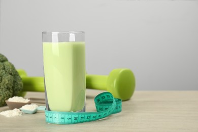 Tasty shake and measuring tape on wooden table, space for text. Weight loss