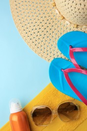 Flat lay composition with sunscreen and different beach accessories on light blue background