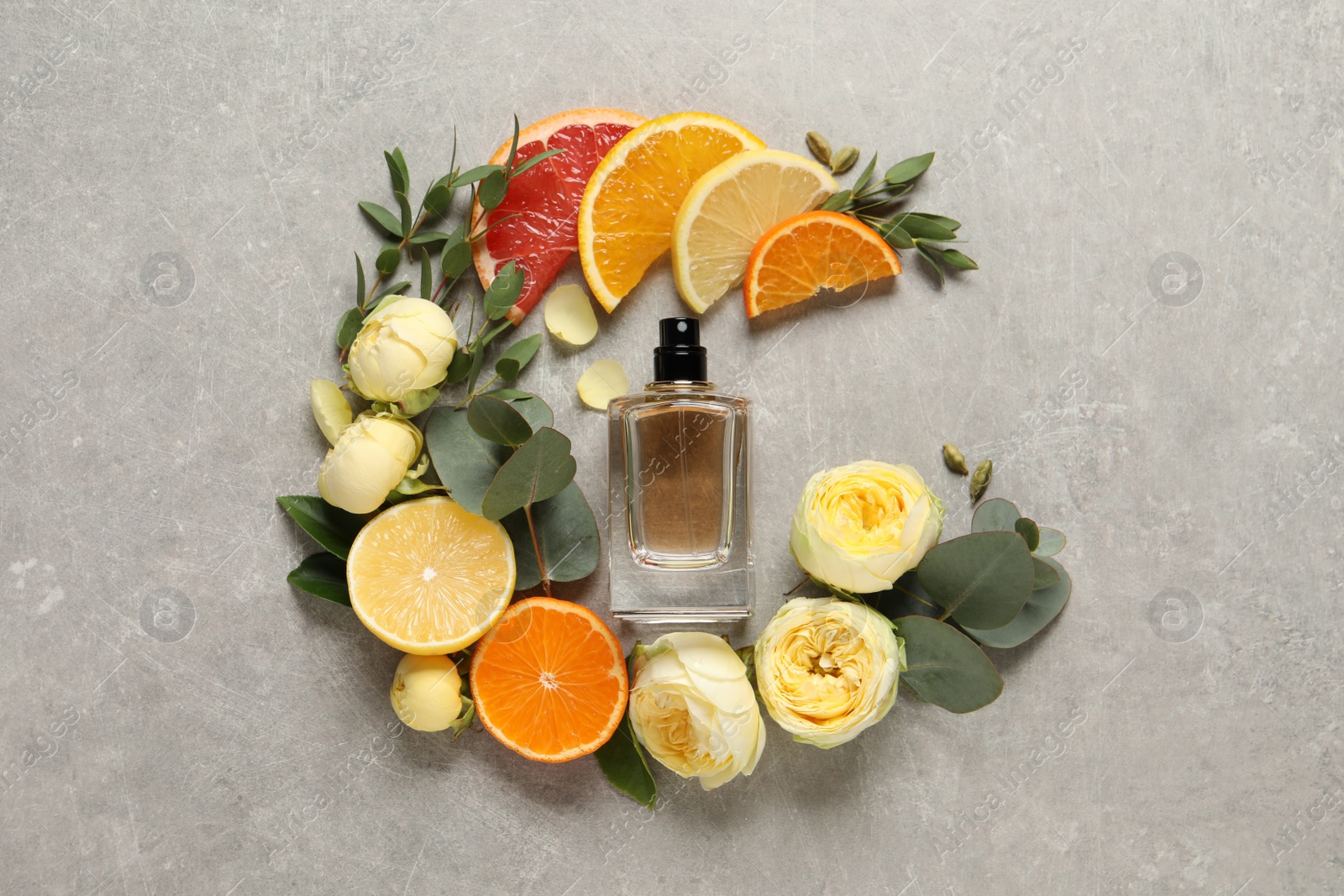 Photo of Flat lay composition with bottle of perfume and fresh citrus fruits on light grey table