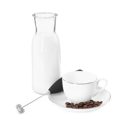 Photo of Mini mixer (milk frother), cup, coffee beans and bottle isolated on white