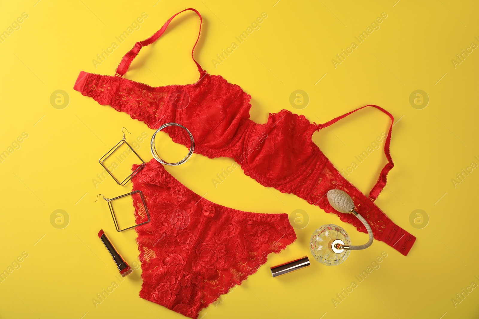 Photo of Elegant red women's underwear, perfume and accessories on yellow background, flat lay