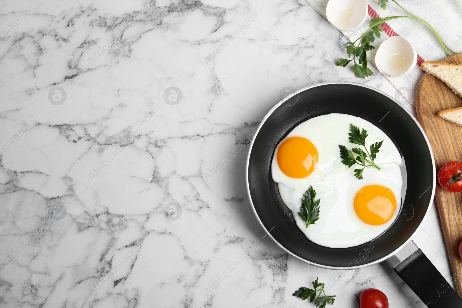 Photo of Tasty cooked chicken eggs with parsley in frying pan on white marble table, flat lay. Space for text