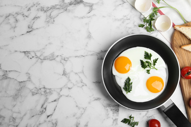 Photo of Tasty cooked chicken eggs with parsley in frying pan on white marble table, flat lay. Space for text