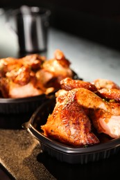 Photo of Cooked pieces of grilled chicken in plastic containers on bar counter. Food delivery service