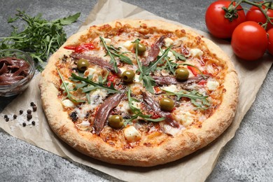 Photo of Tasty pizza with anchovies and ingredients on grey table