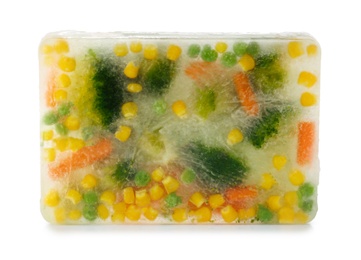 Photo of Fresh vegetables frozen in ice cube on white background