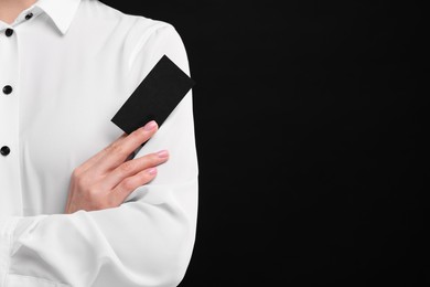 Photo of Woman holding blank business card on black background, closeup. Space for text