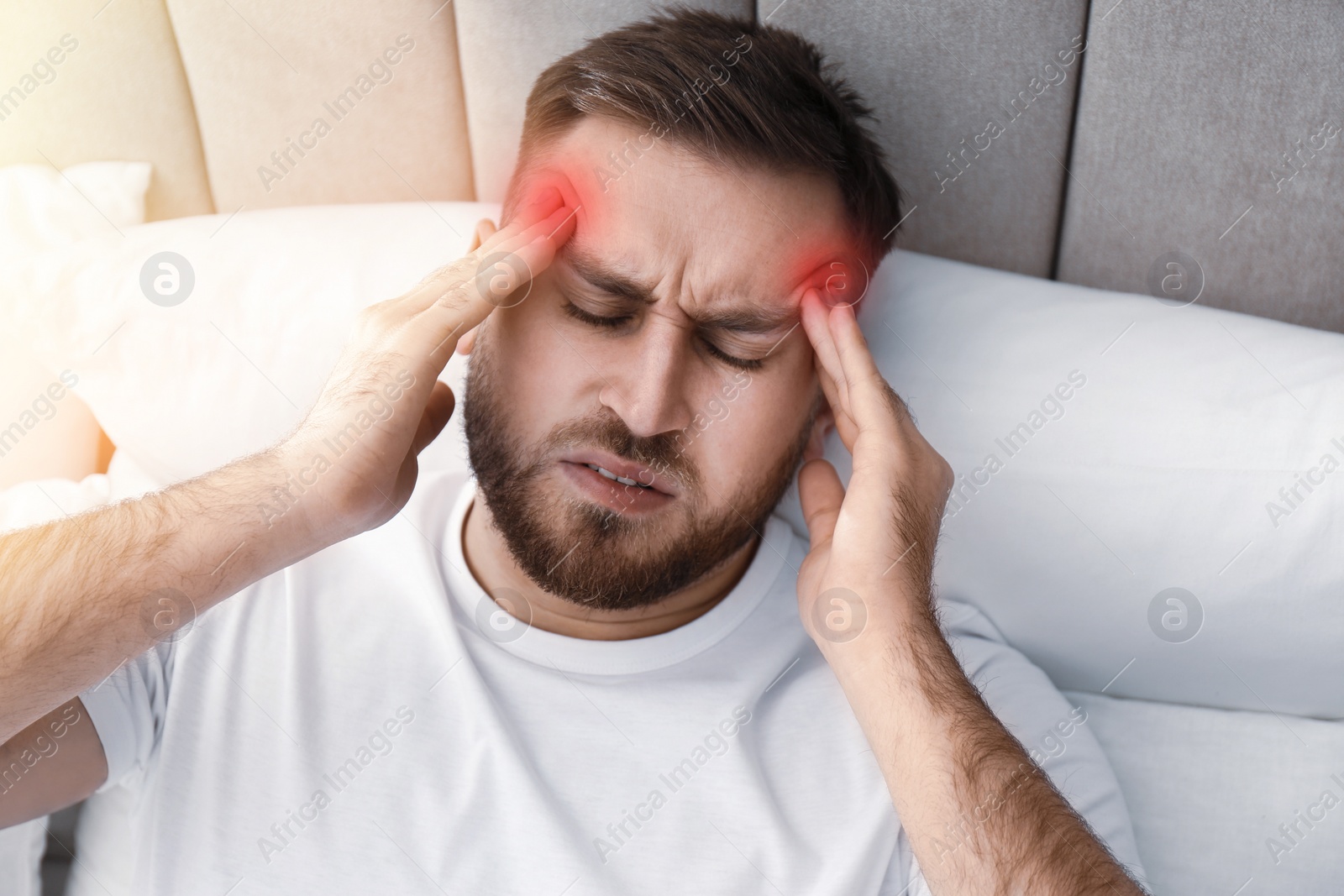 Image of Young man suffering from migraine in bed, above view
