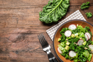 Photo of Delicious kale salad on wooden table, flat lay. Space for text