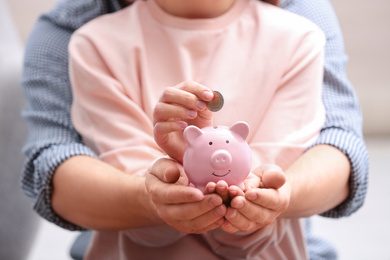 Photo of Couple with piggy bank and coin, closeup