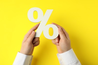 Photo of Man holding percent sign on yellow background, closeup