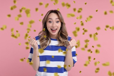 Happy woman and flying confetti on pink background