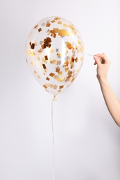 Woman piercing balloon with needle on white background, closeup