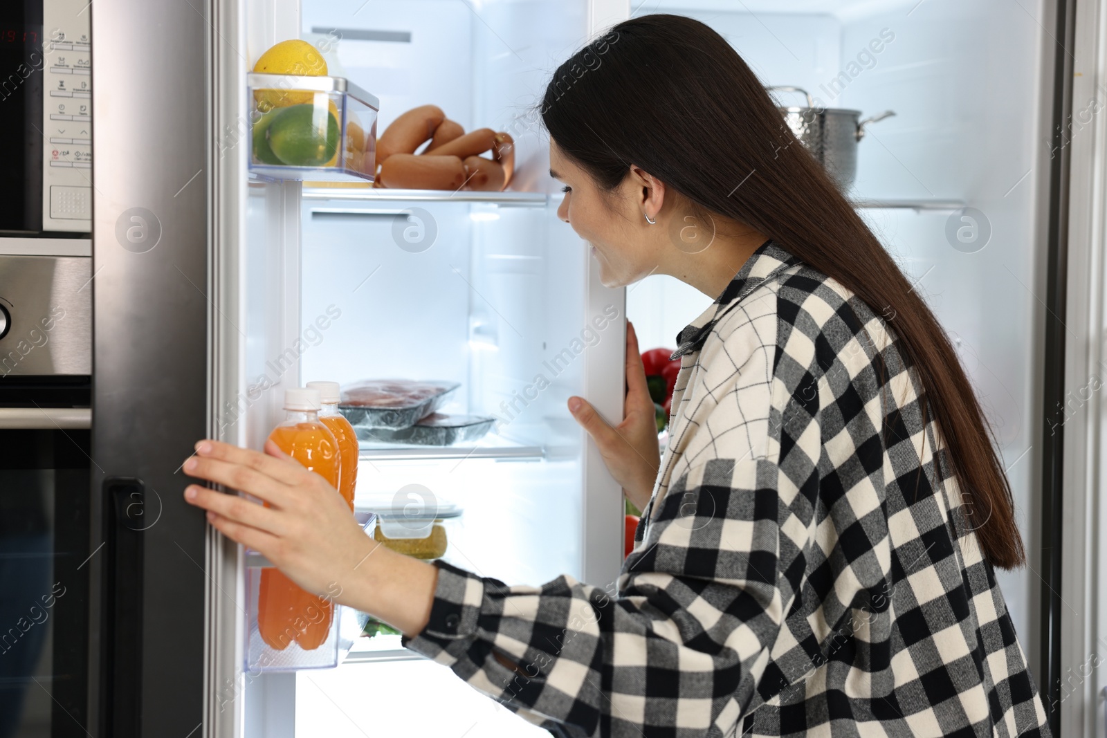 Photo of Young woman near modern refrigerator in kitchen