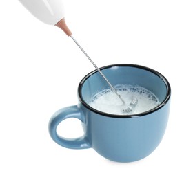 Photo of Whisking milk in cup with mini mixer (frother wand) isolated on white, closeup